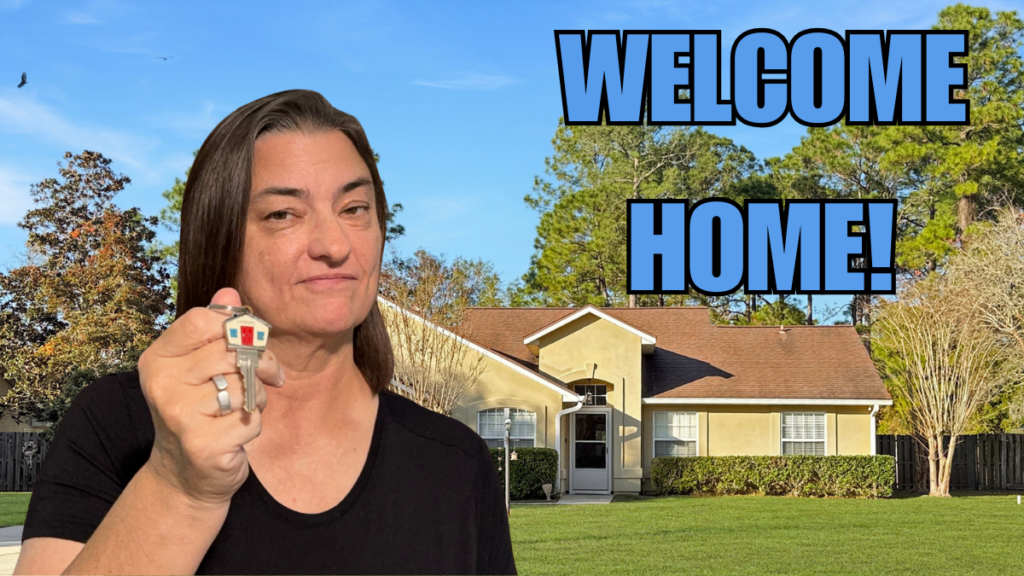 A picture of Pam Graham holding keys with her listing at 976 Deer Chase in the background. Text that says Welcome Home!